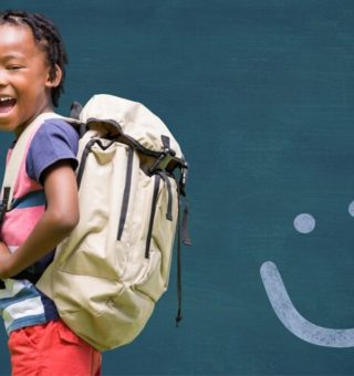 Um menino está sorrindo com sua Mochila Escolar Infantil nas costas
