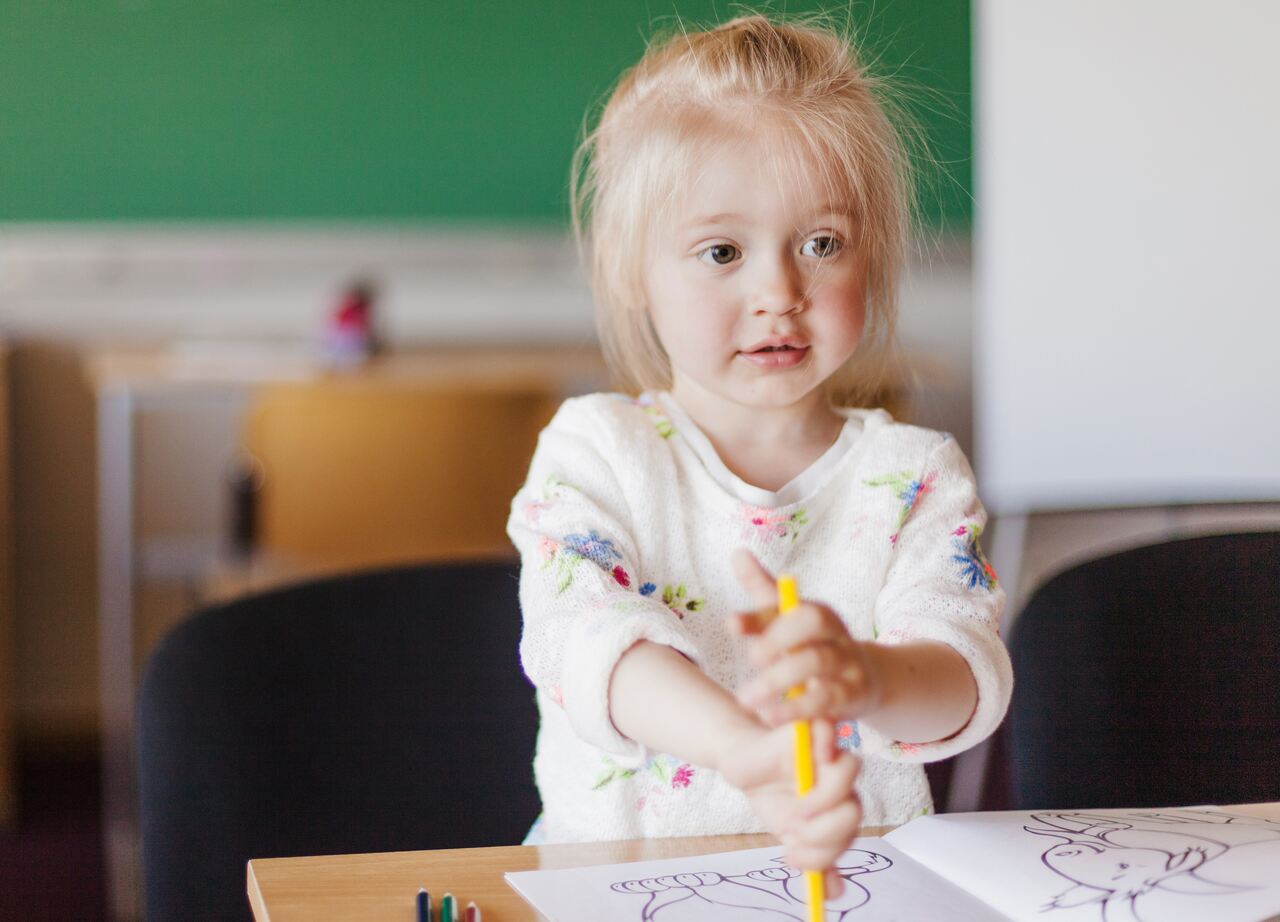 Criança desenha sentada em sua mesa na creche